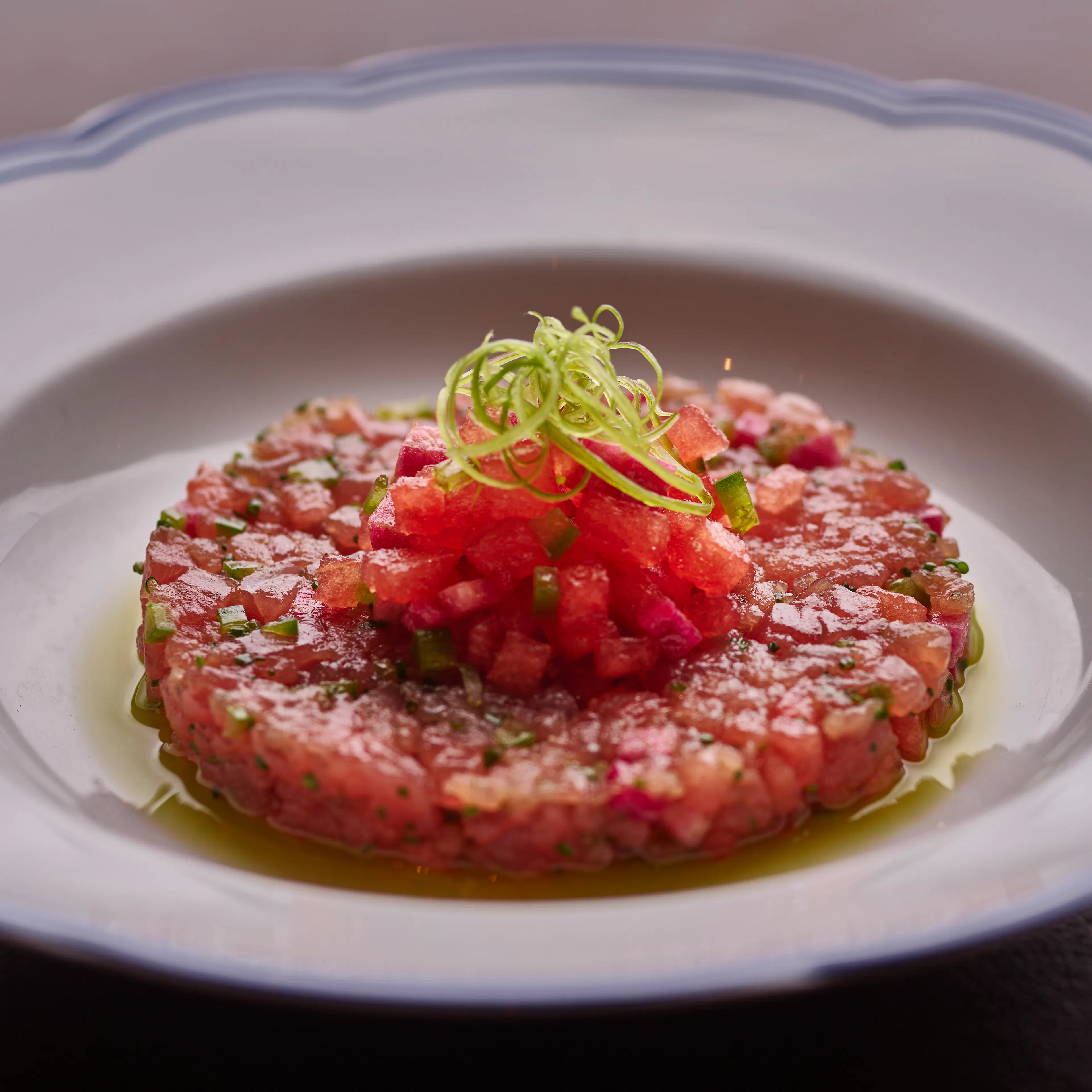 Yellowfin tuna tartare with watermelon, radish, and lemon verbena, artfully plated with fresh seasonal garnishes.