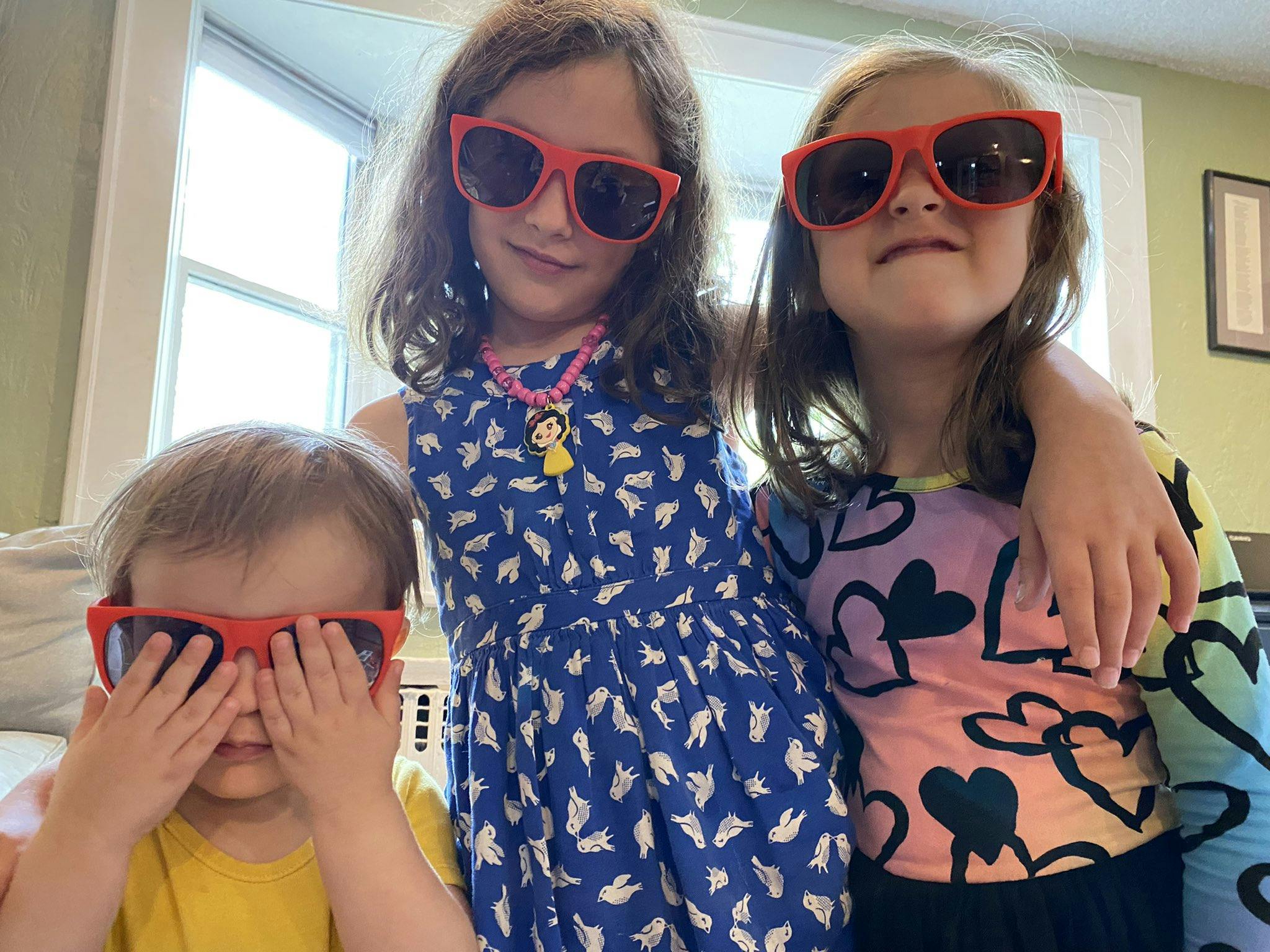 Three young kids posing for the camera in oversized sunglasses.