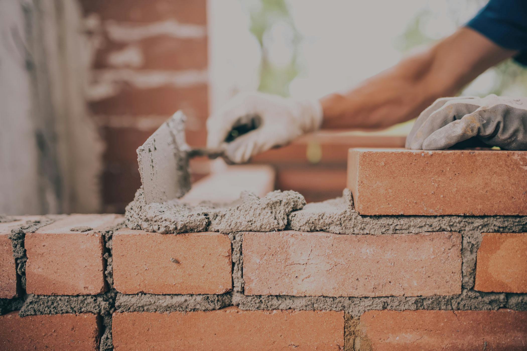 A worker stacks a brick wall.