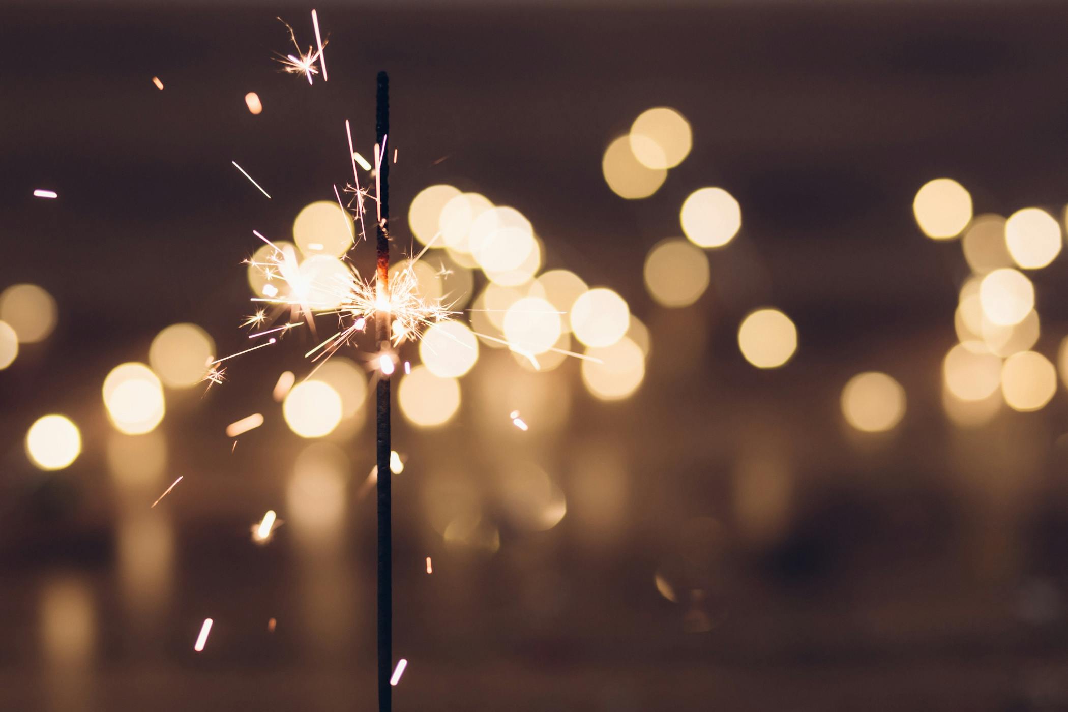 A lit sparkler with party lights in the background