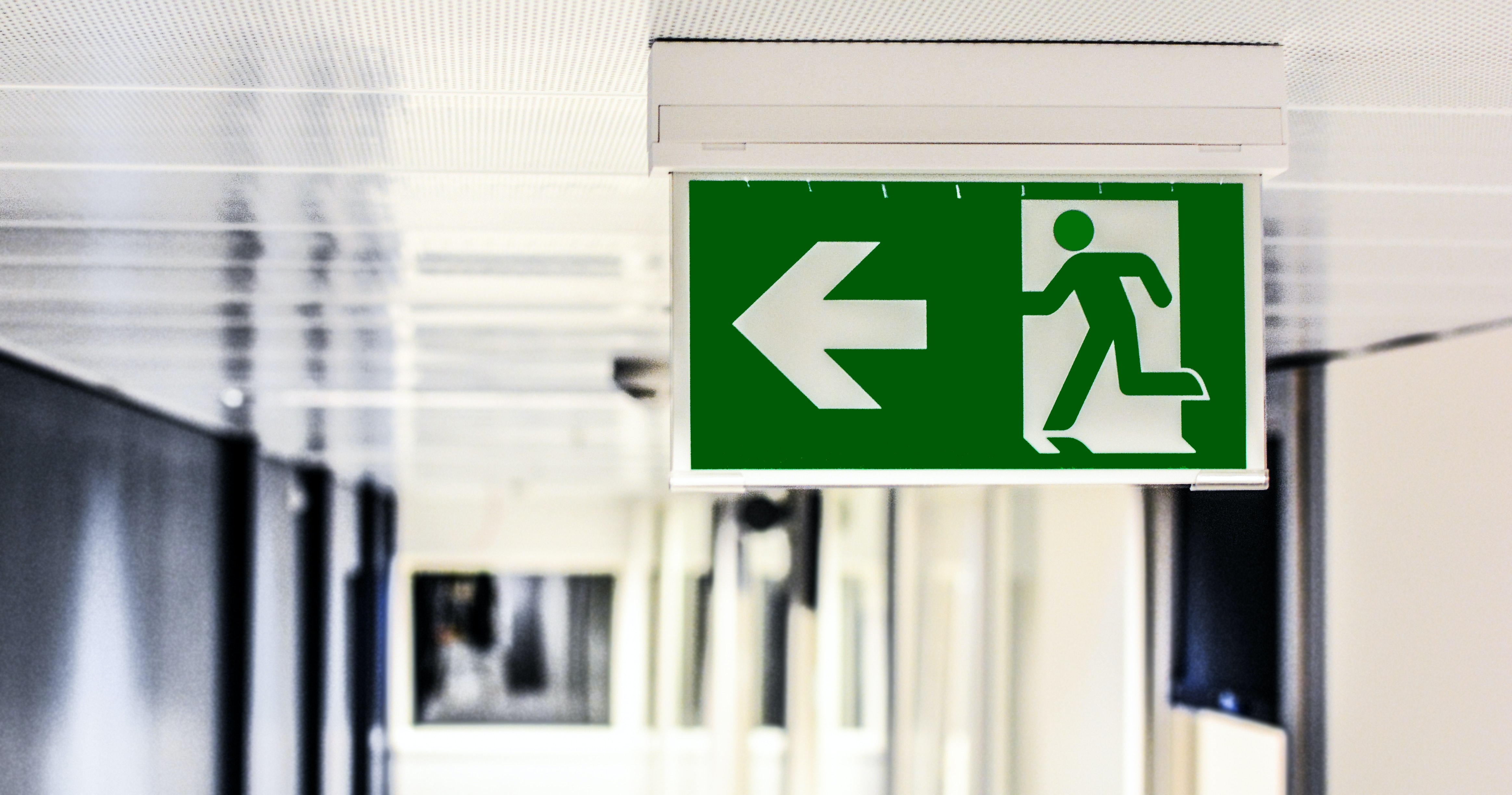 Green and white sign with an arrow pointing in the direction of the exit