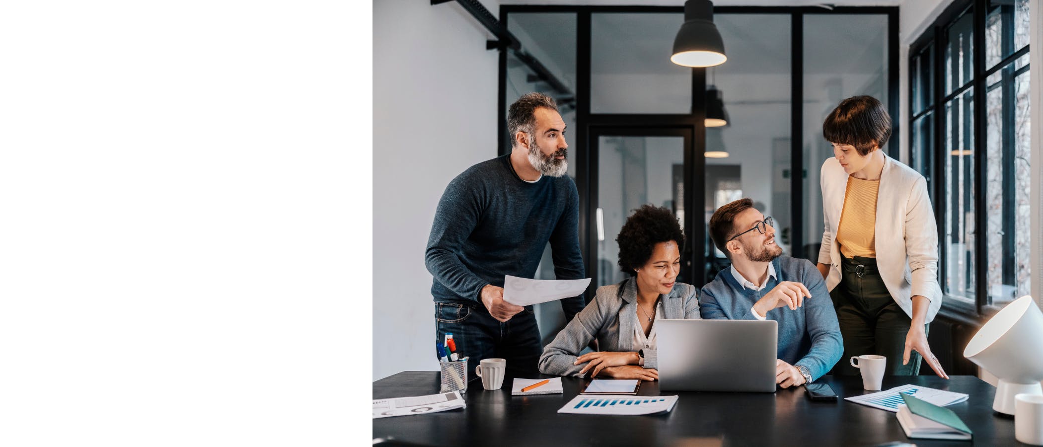 Employees talk animatedly in front of an open laptop.