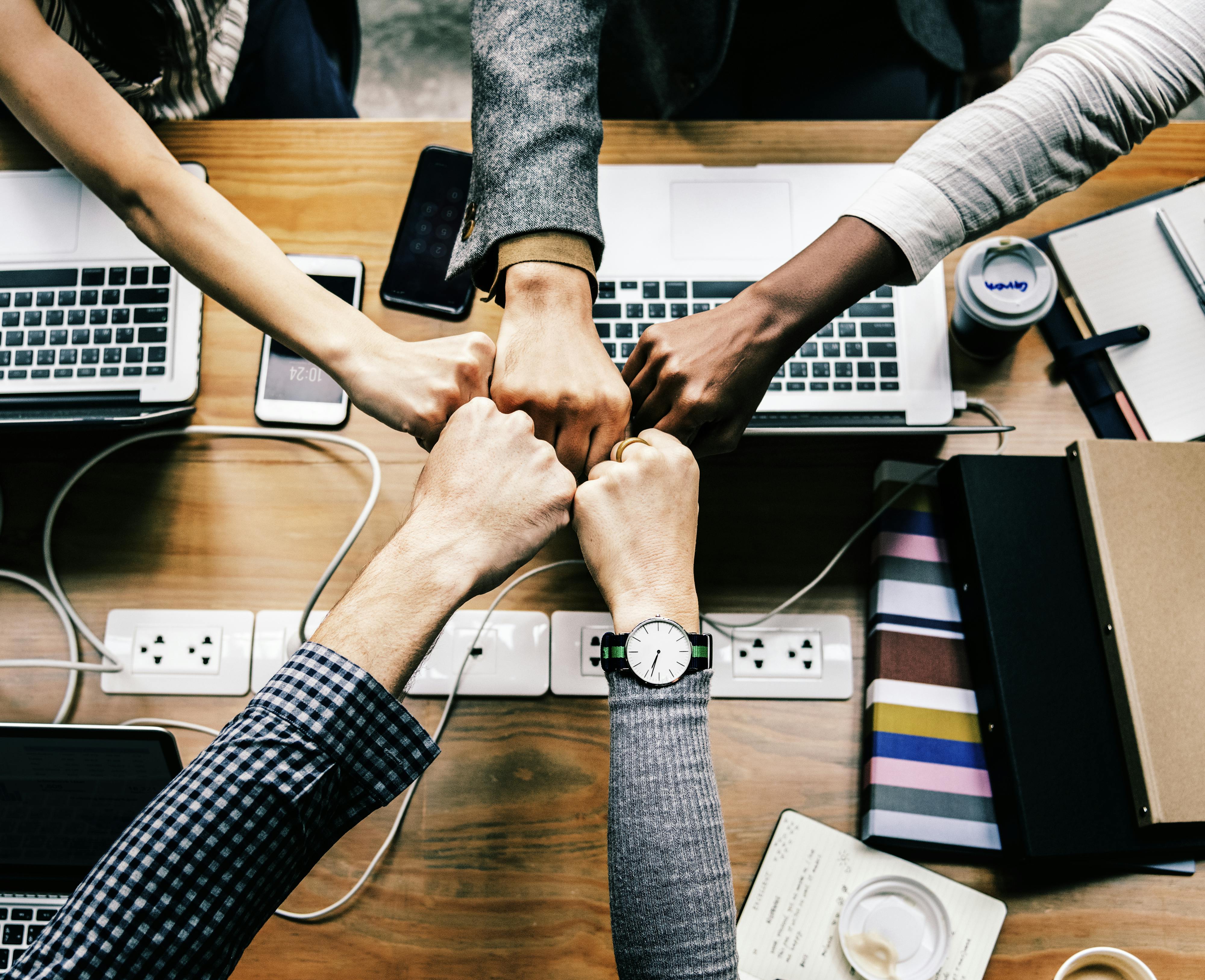 Group of people bumping fists in agreement while collaborating