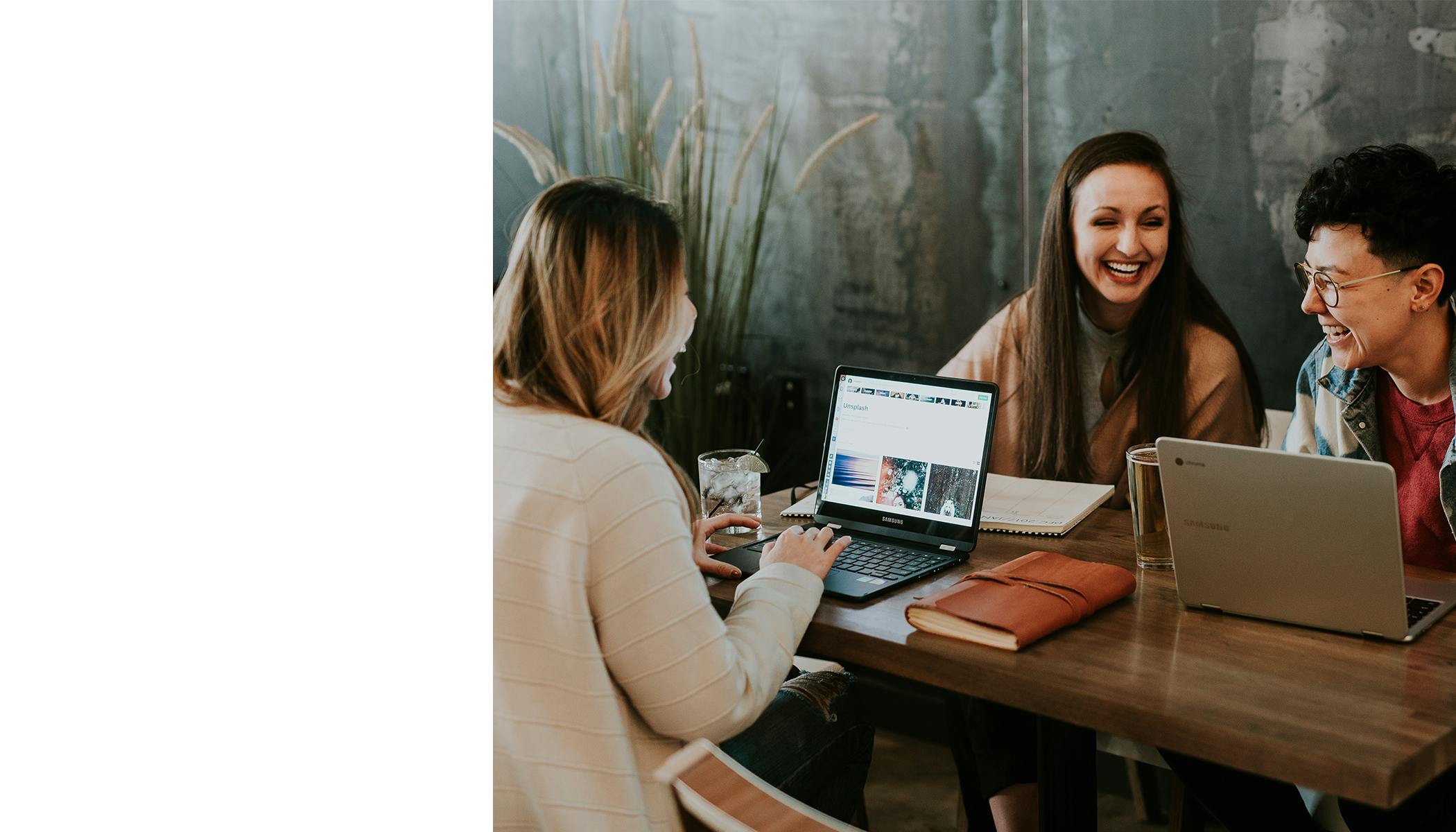 Photo of three people sitting at a table laughing together