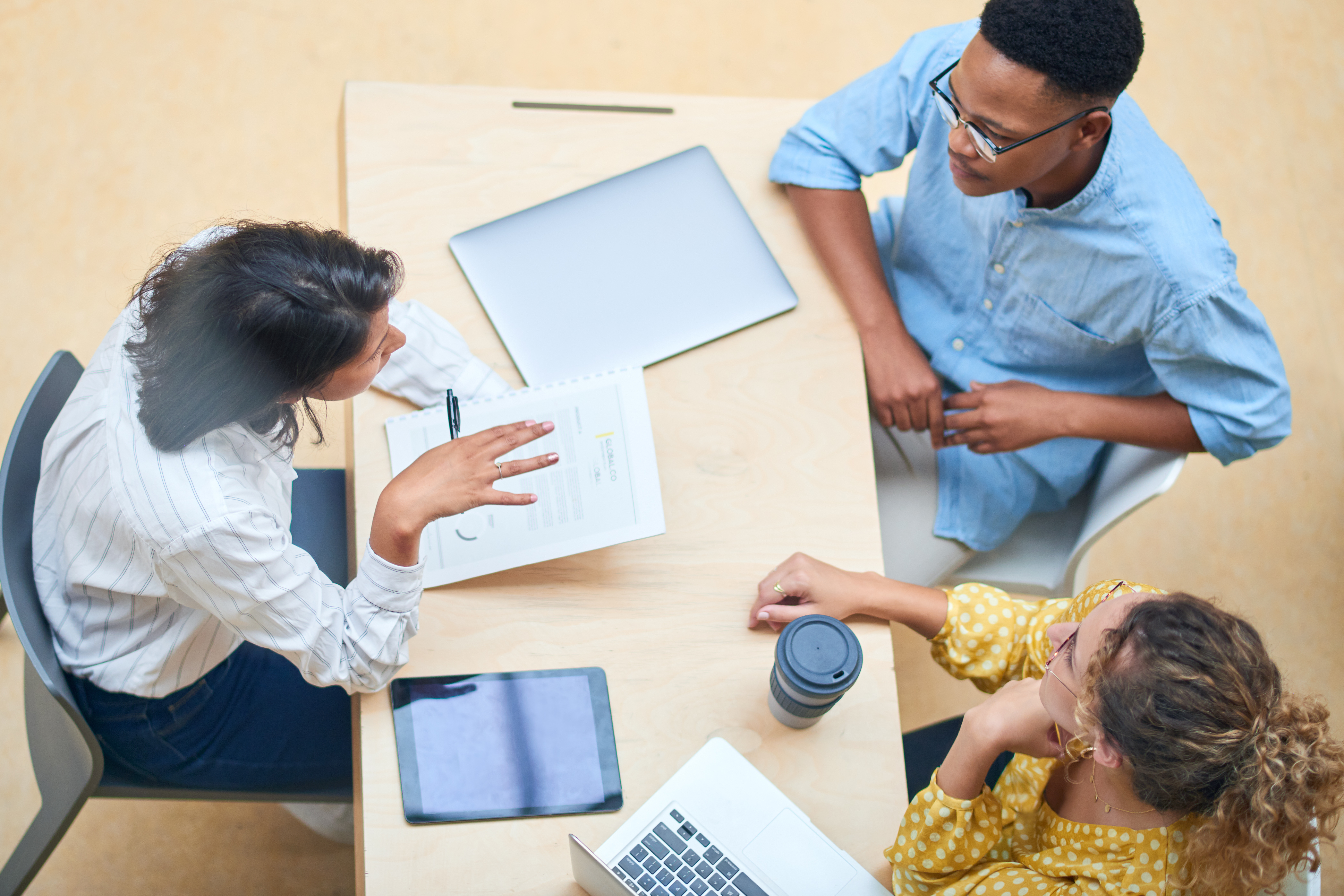 Documents are seen as three employees talk.
