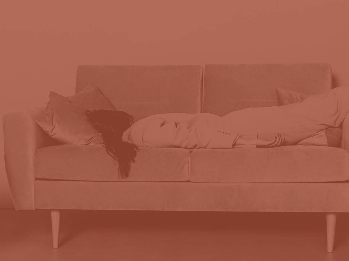 A woman is lying face-down on a sofa.