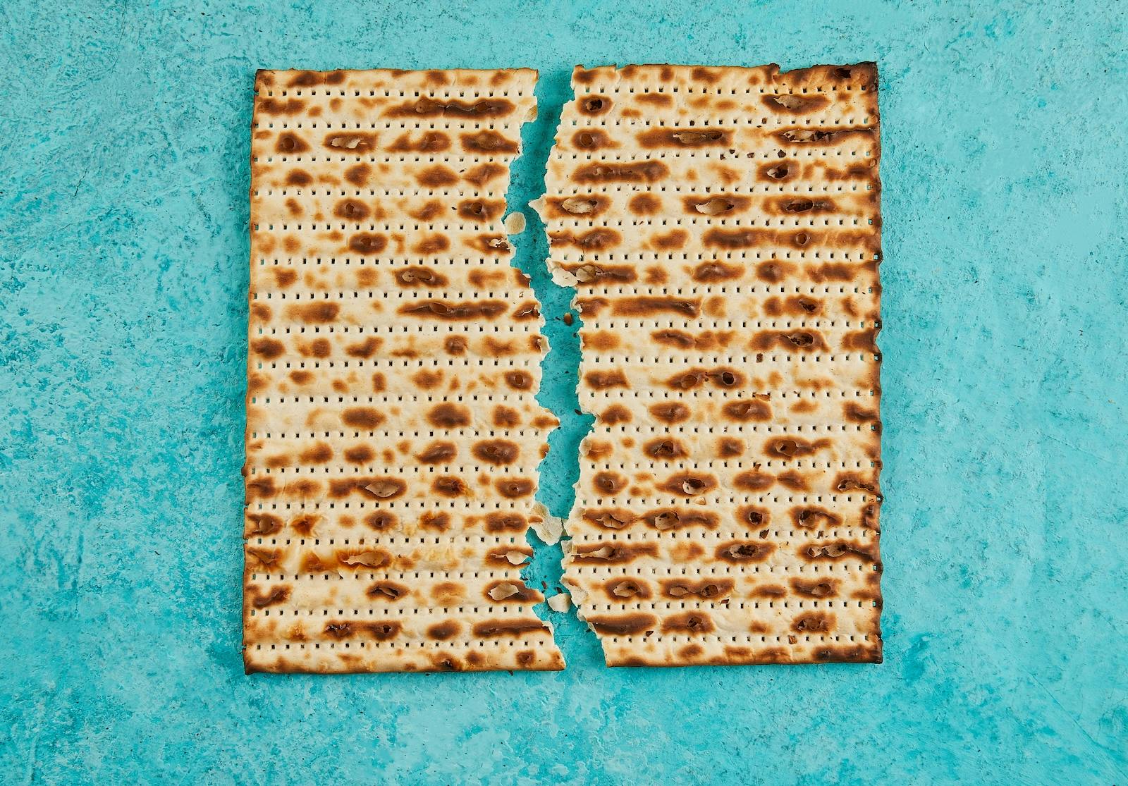 A broken piece of matzah on a teal background