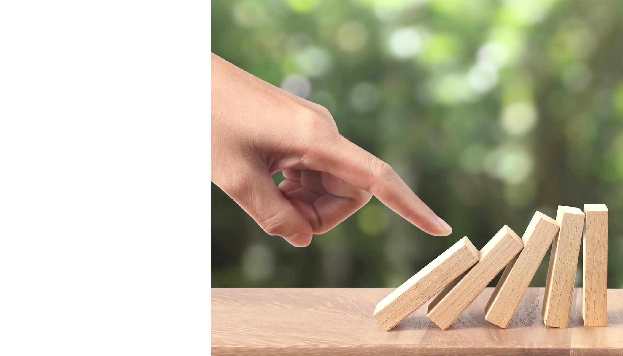 A hand topples over wooden dominoes.
