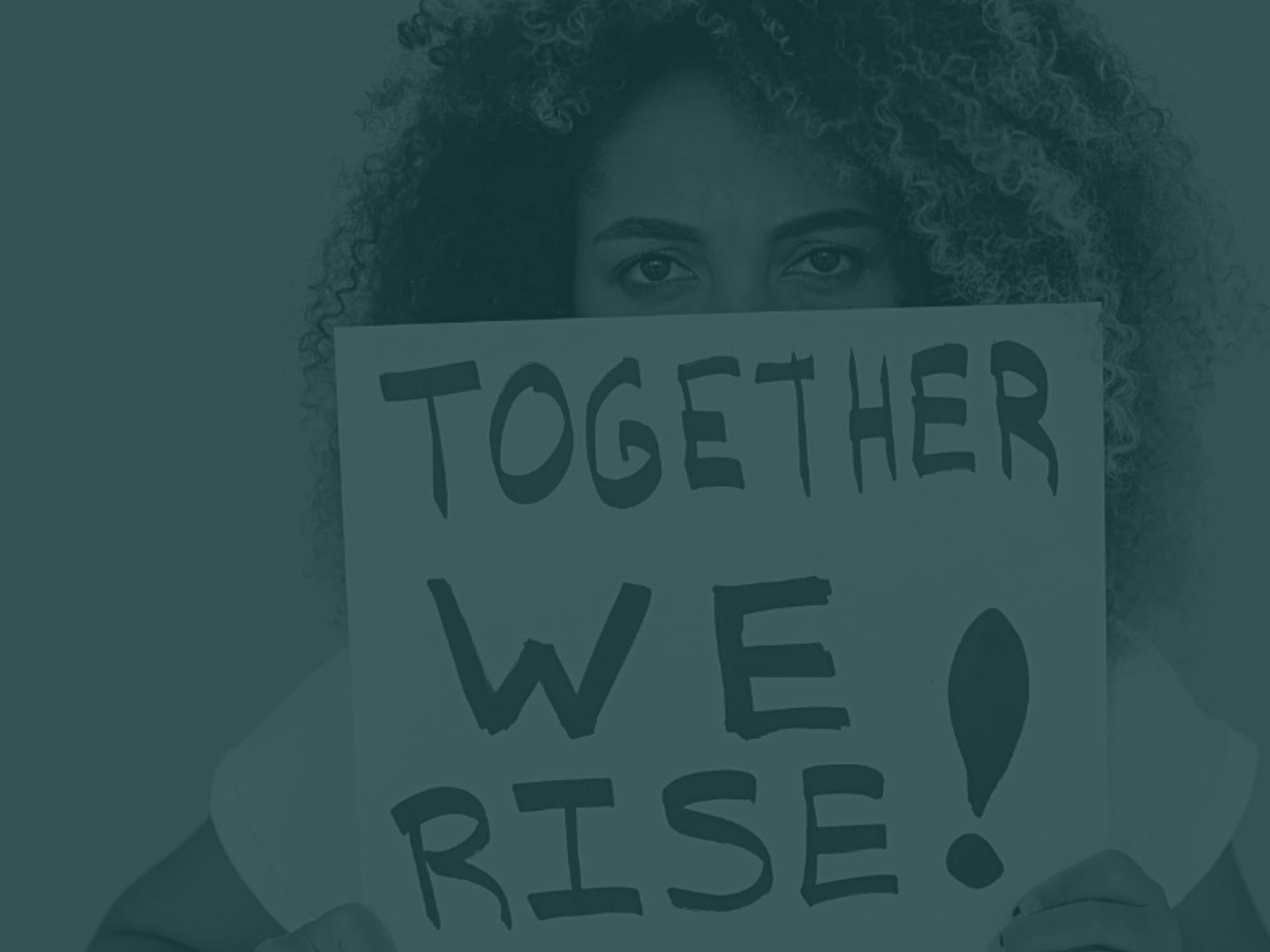 A woman holds a sign reading, "TOGETHER WE RISE!"