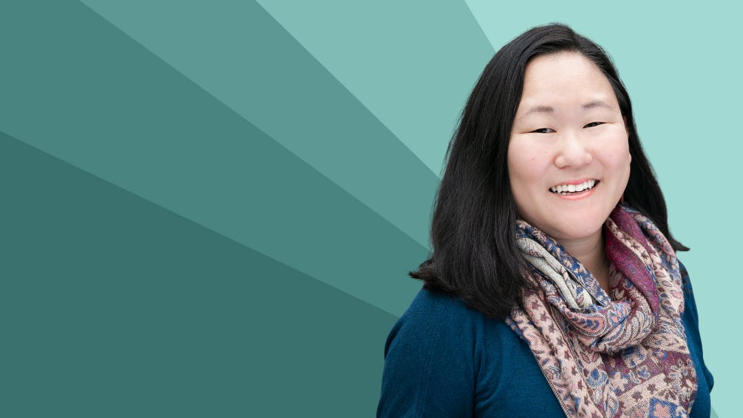 Image of Jess Greenblatt Seeley smiling against a teal geometric background.