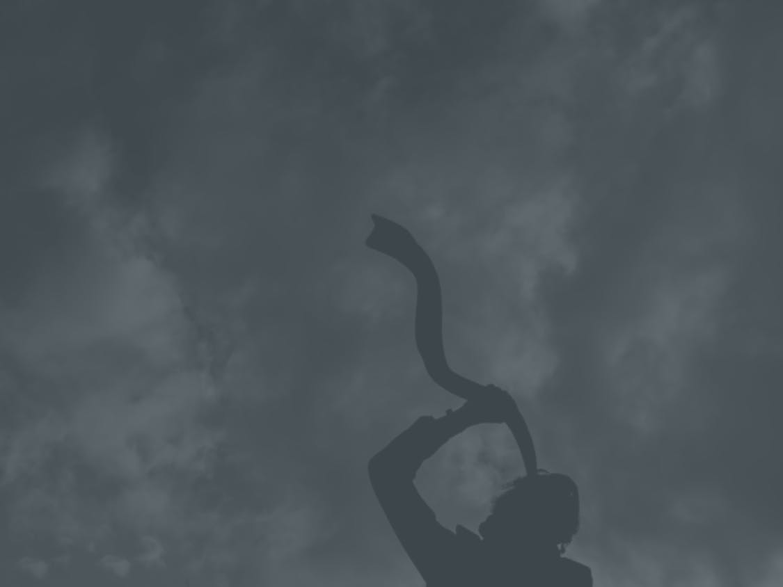 A Jewish man blows a shofar.