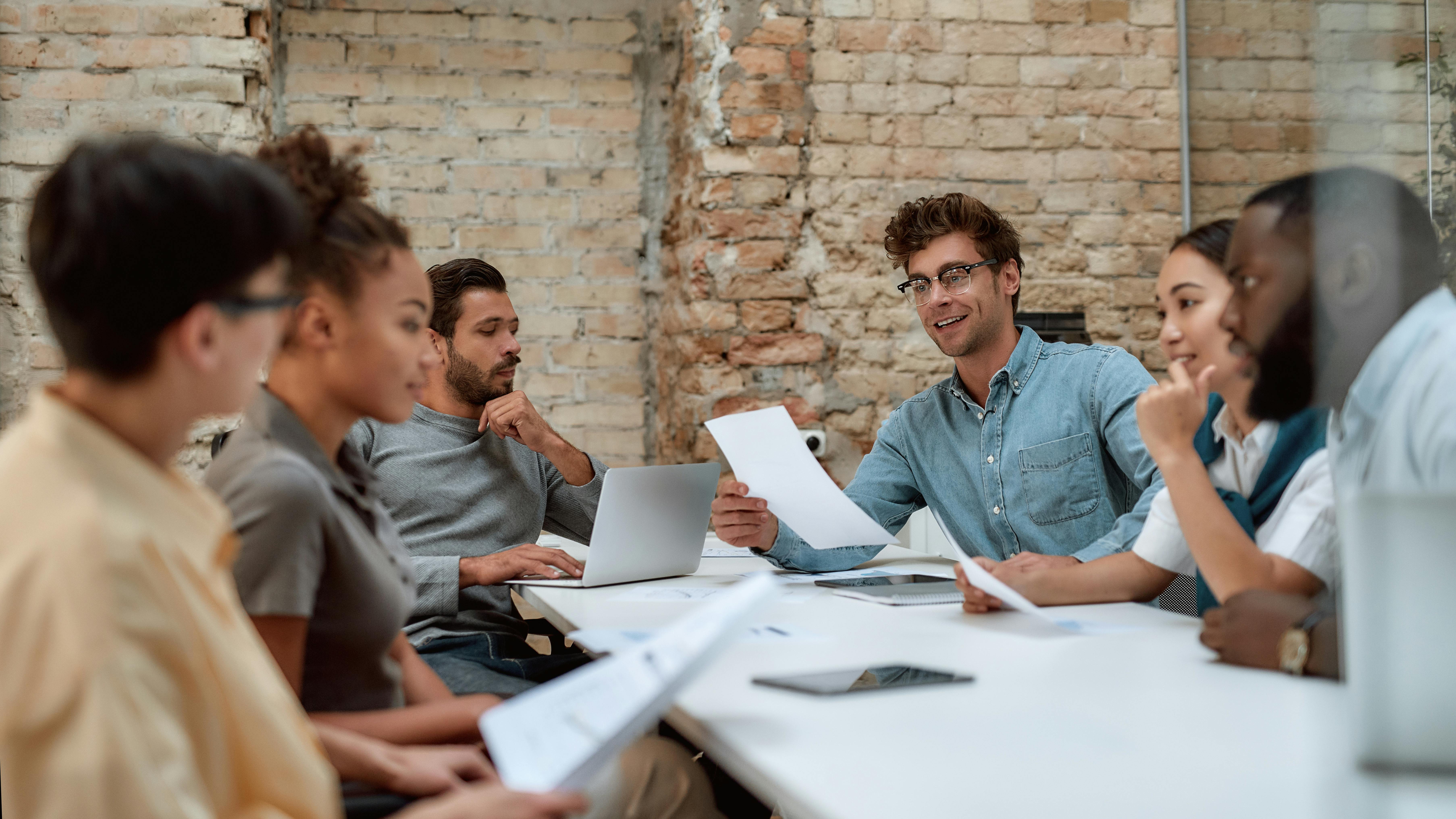 A group of young professionals talk during a meeting.