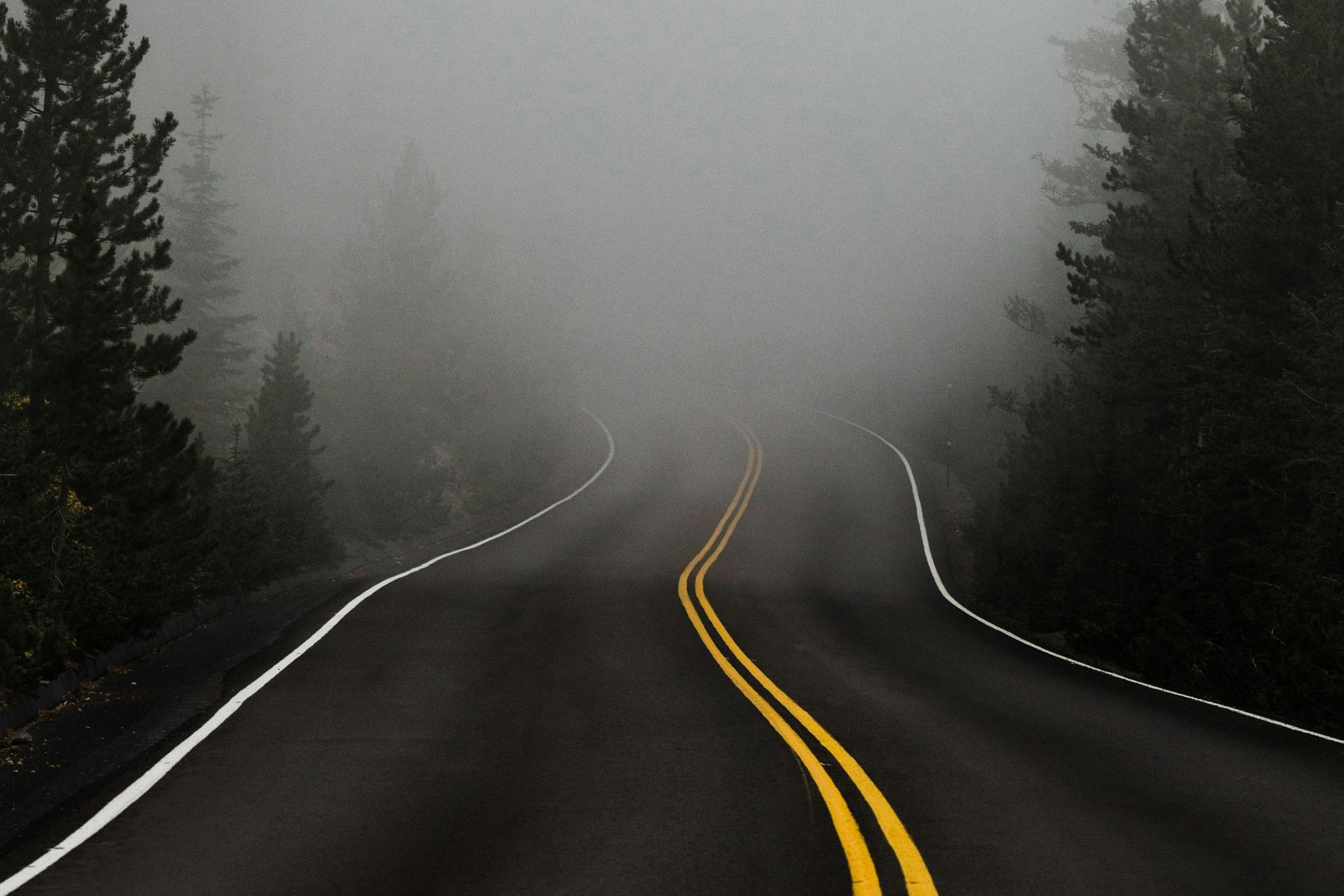 A 2-lane road leading into a foggy mist