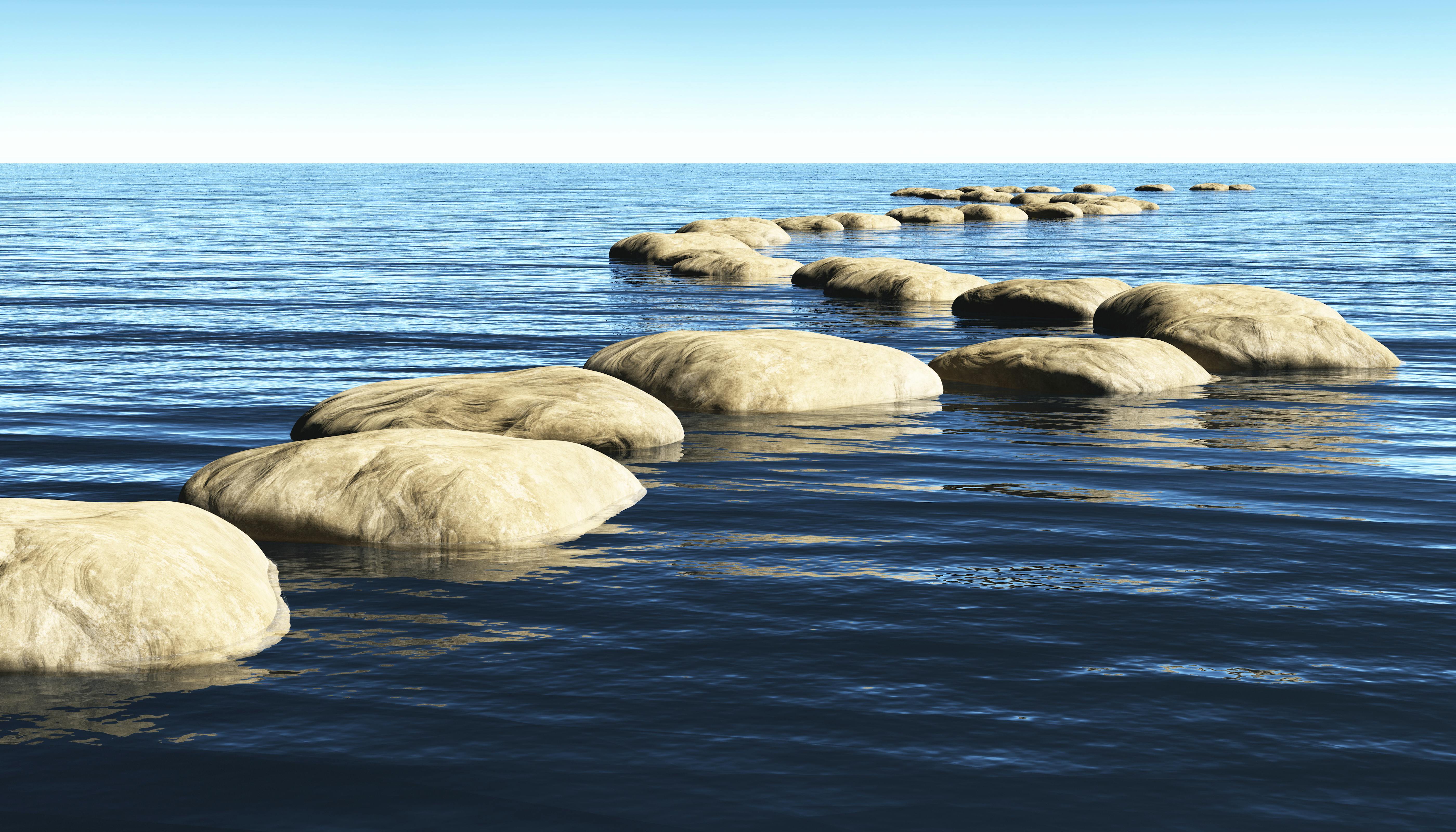 A path made of stones that stay above the surface of deep water and leads toward the horizon