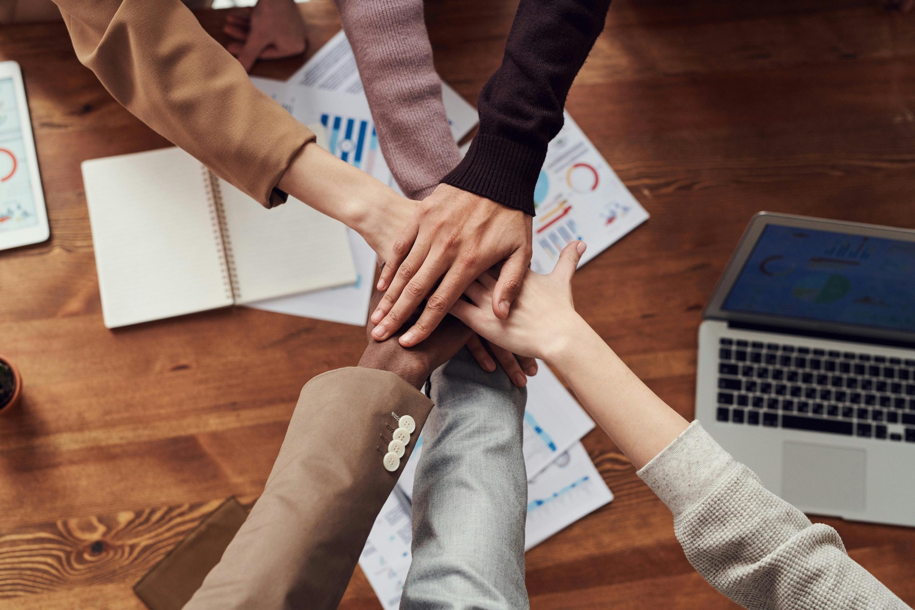 Photo: A group of people stacking hands at a huddle