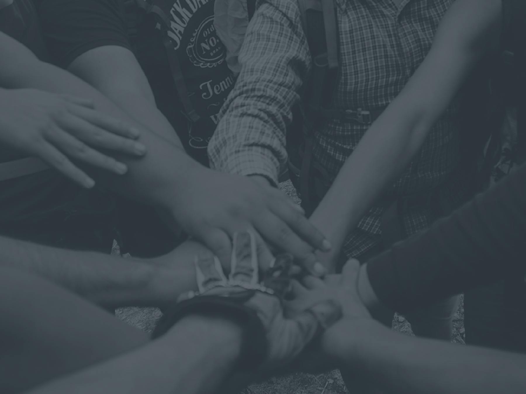 A group gathers their hands together in a huddle.