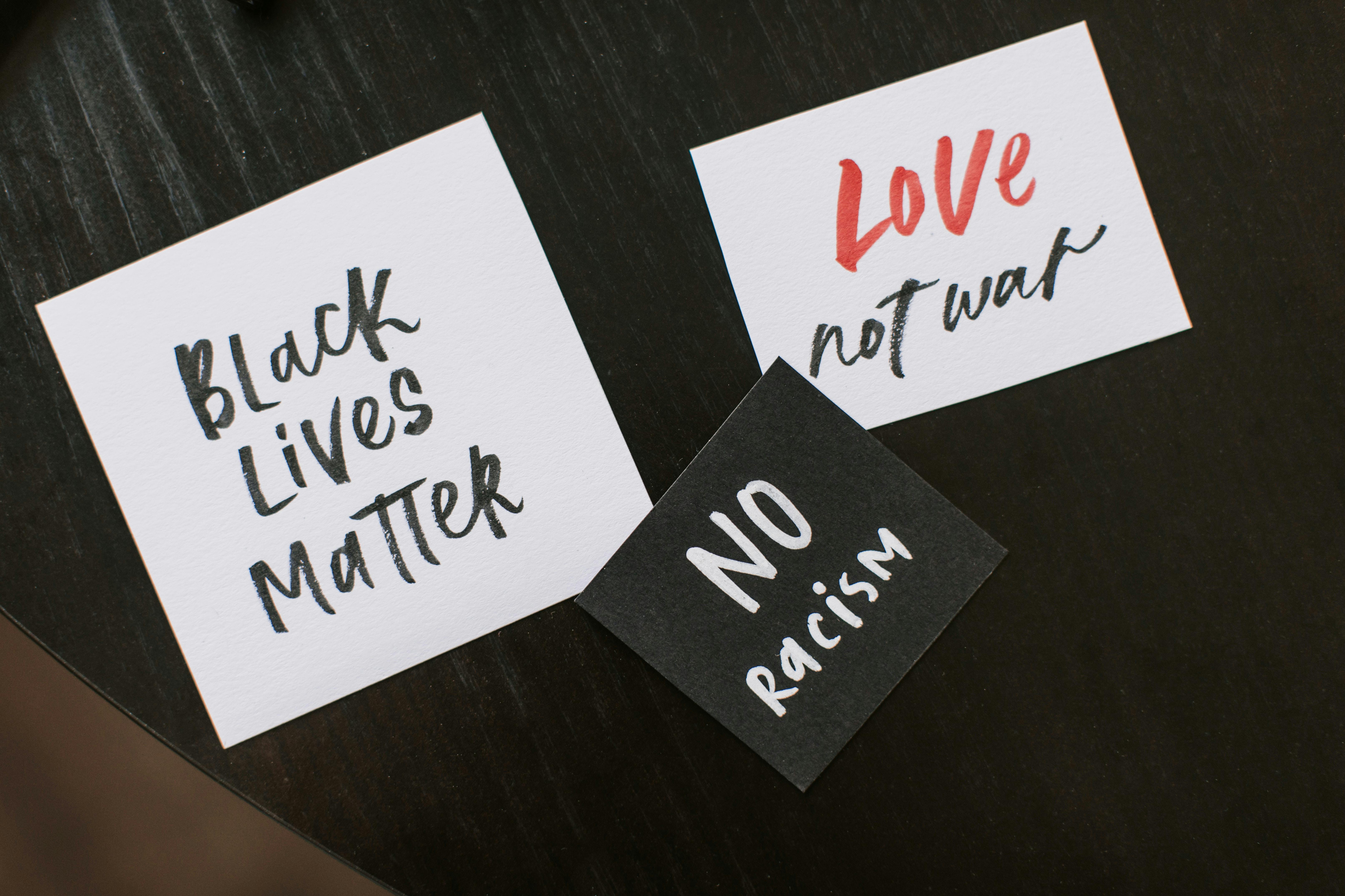 Handwritten text on post-it notes "Black Lives Matter," "Love not war," "No racisim."