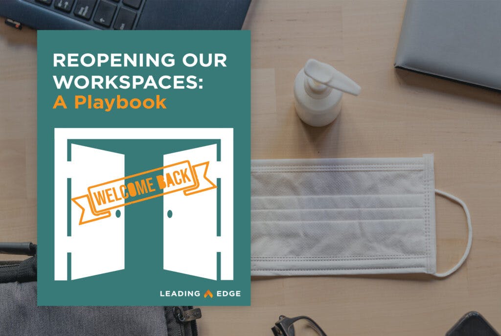 A group of items on a desk: disposable face mask, hand sanitizer, eye glasses and a laptop