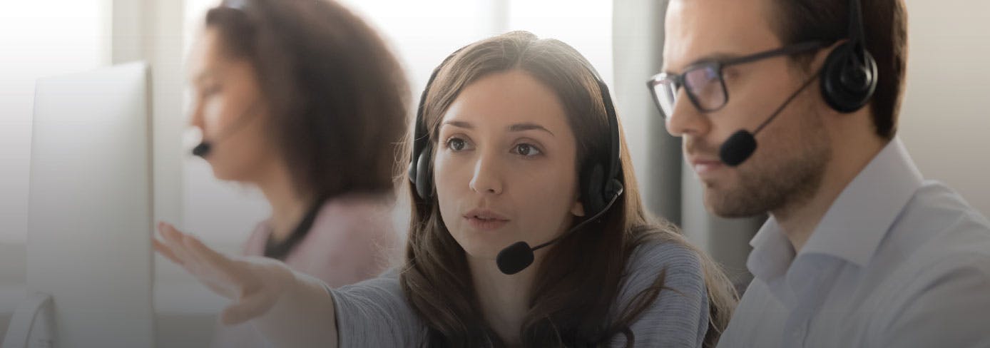 Photo: people wearing microphone headsets and discussing a shared computer screen