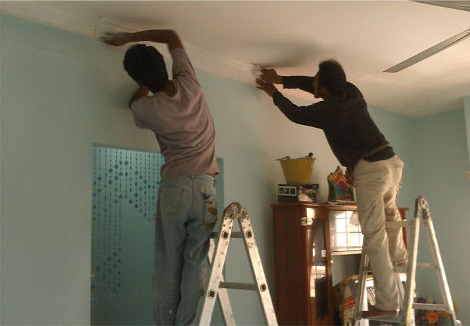 Artisans rénovant un plafond en plâtre.