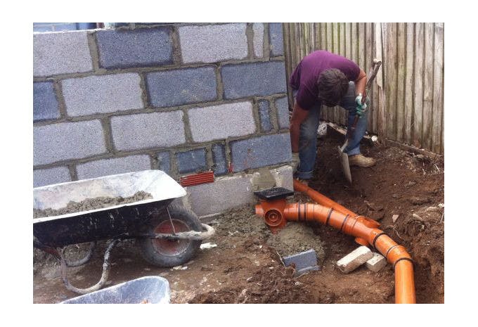 Plombier effectuant des raccordements sanitaires lors d'une construction de maison.