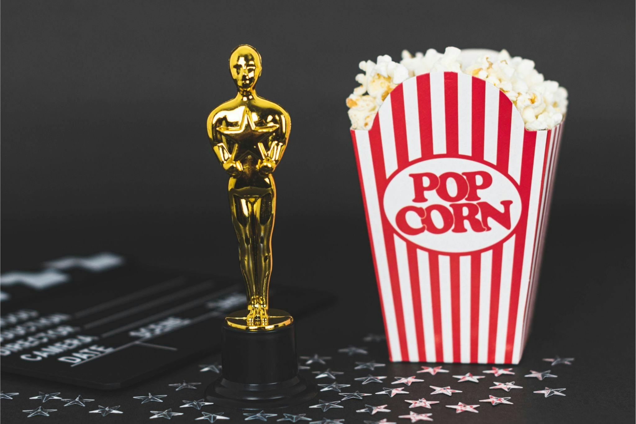 Statuette des oscars avec des popcorns et un clap de cinema et des étoiles