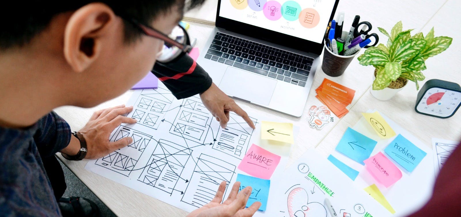 Tafel vol met post-it's, laptop en tekeningen