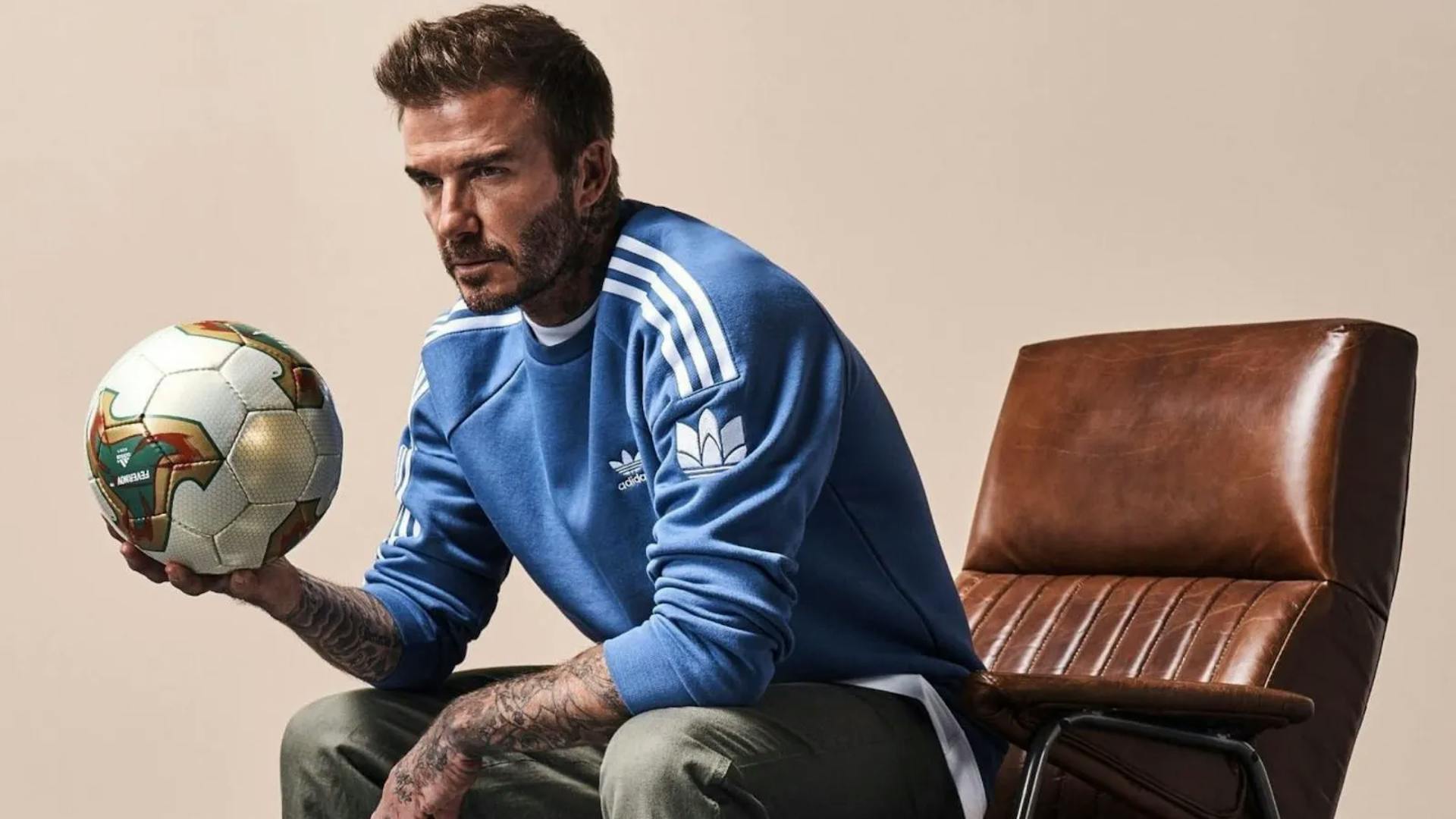 David Beckham sitting in a leather chair holding a football.