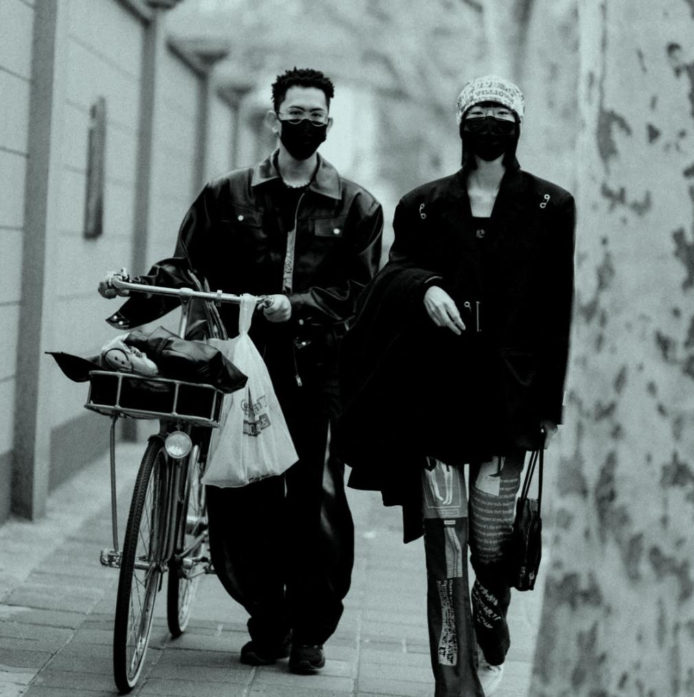Two people walking together with a bike.