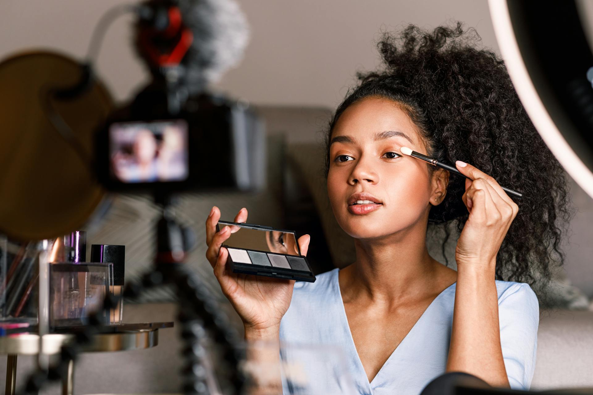 A woman doing her makeup while shooting a video.