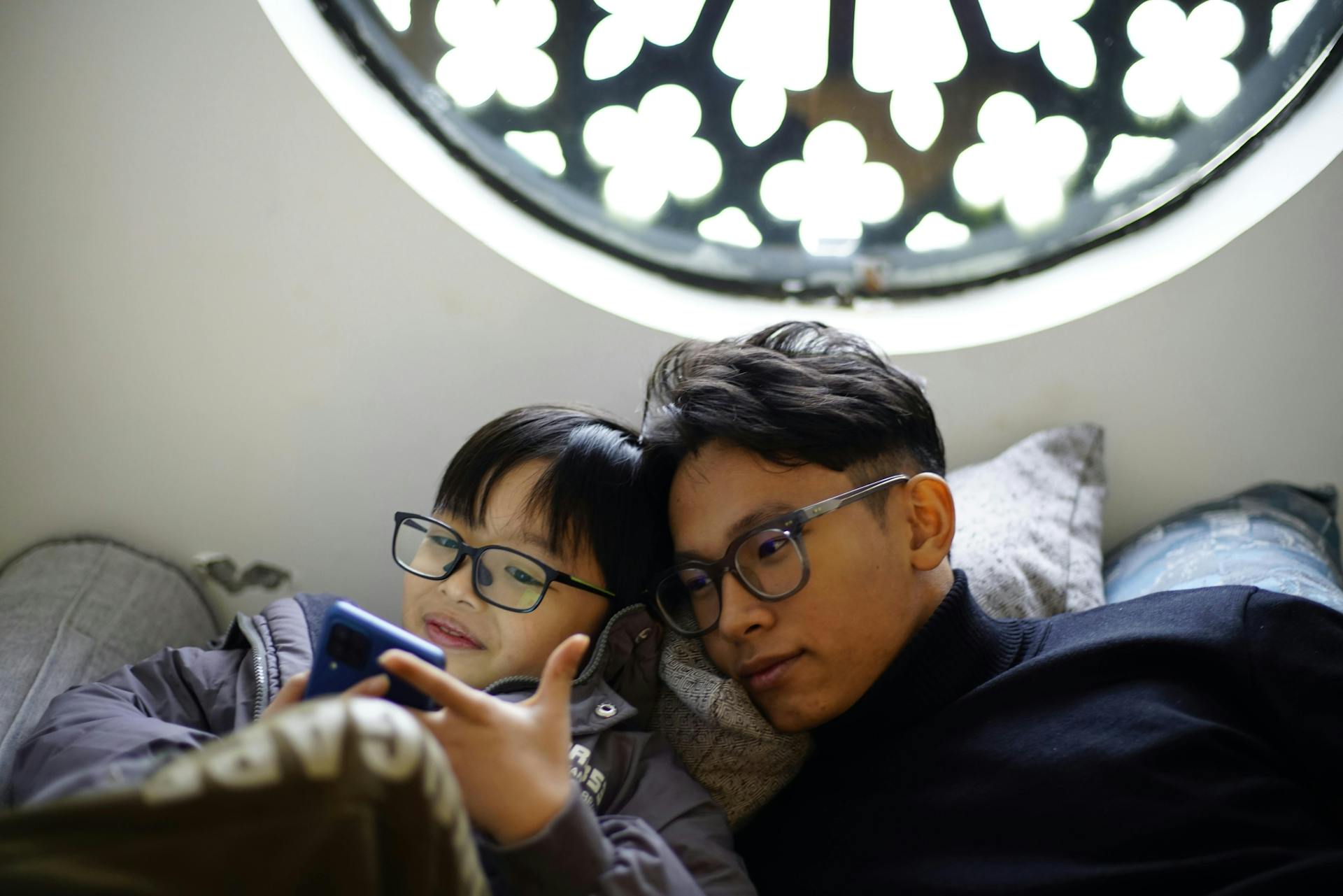 A parent with his child looking at a smartphone.