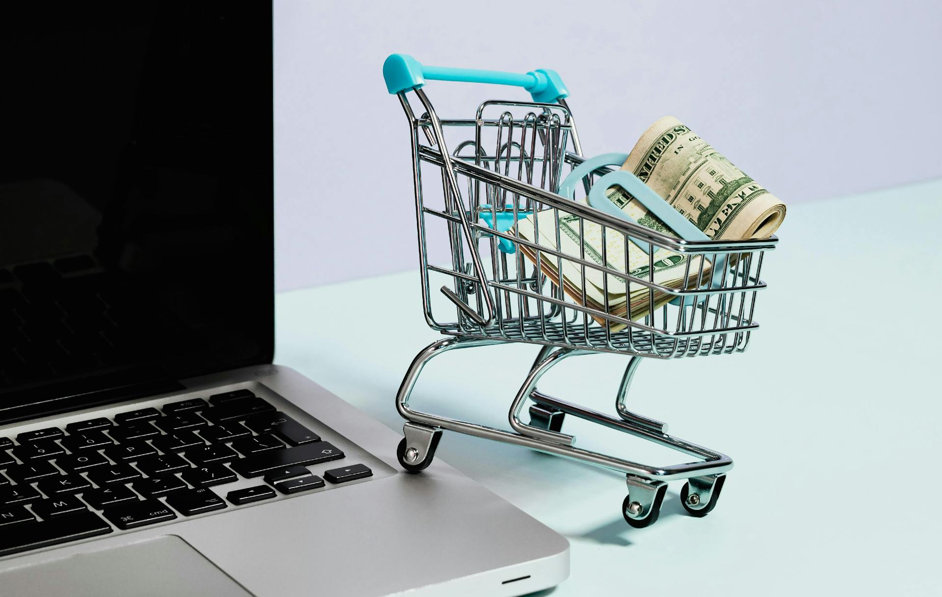 A shopping cart next to a laptop.