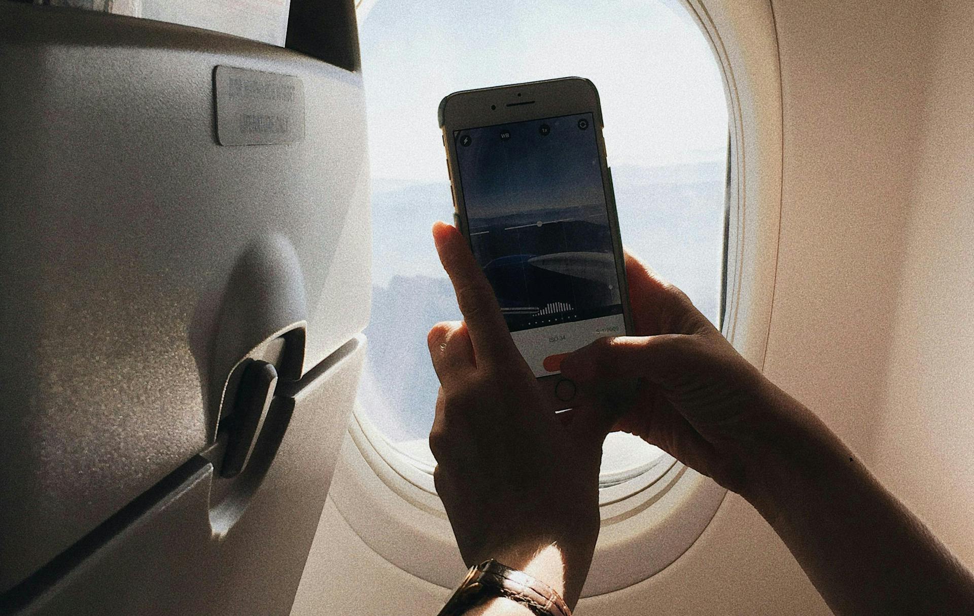 A person taking a picture outside a plane window.