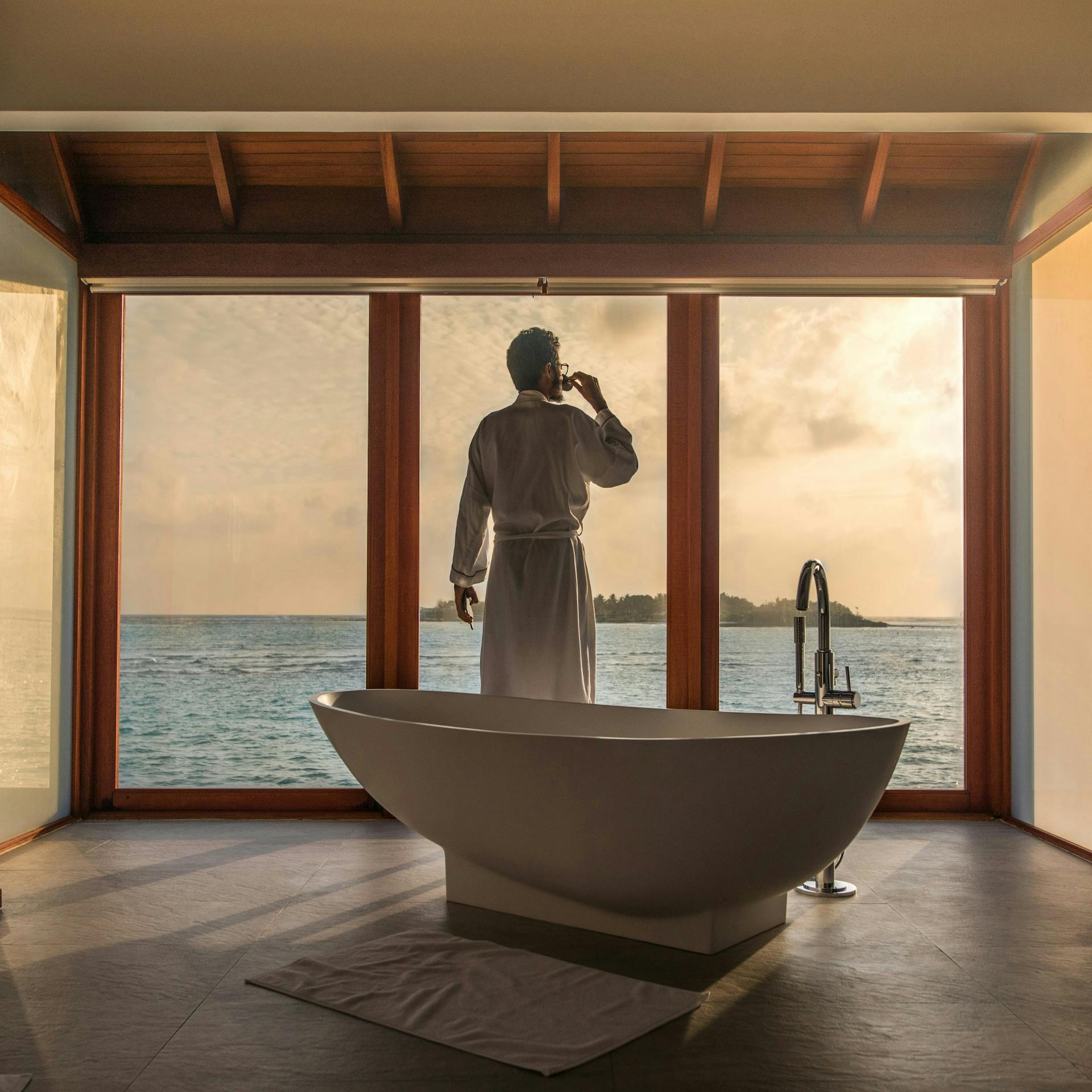 A man in a bathrobe looking at an ocean view.