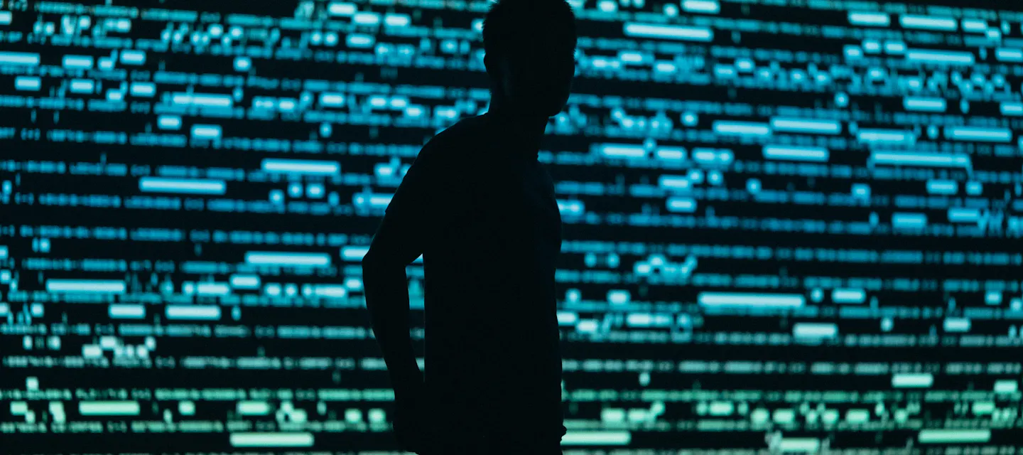 Shadow of a man standing in front of a blue and green grid of data