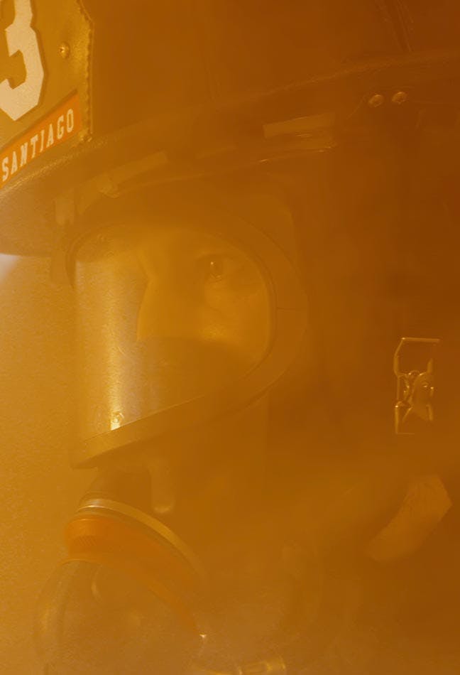 Fire fighter in a smoky area facing a fire