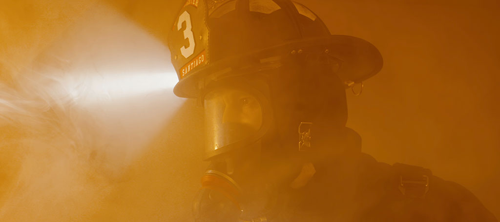 Fire fighter in a smoky area facing a fire