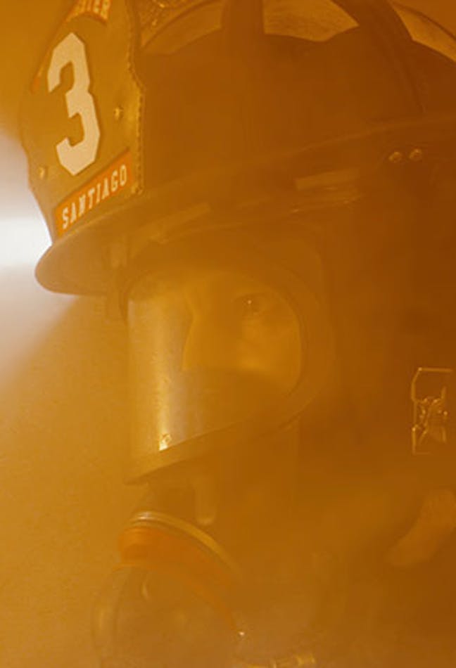 Fire fighter in a smoky area facing a fire