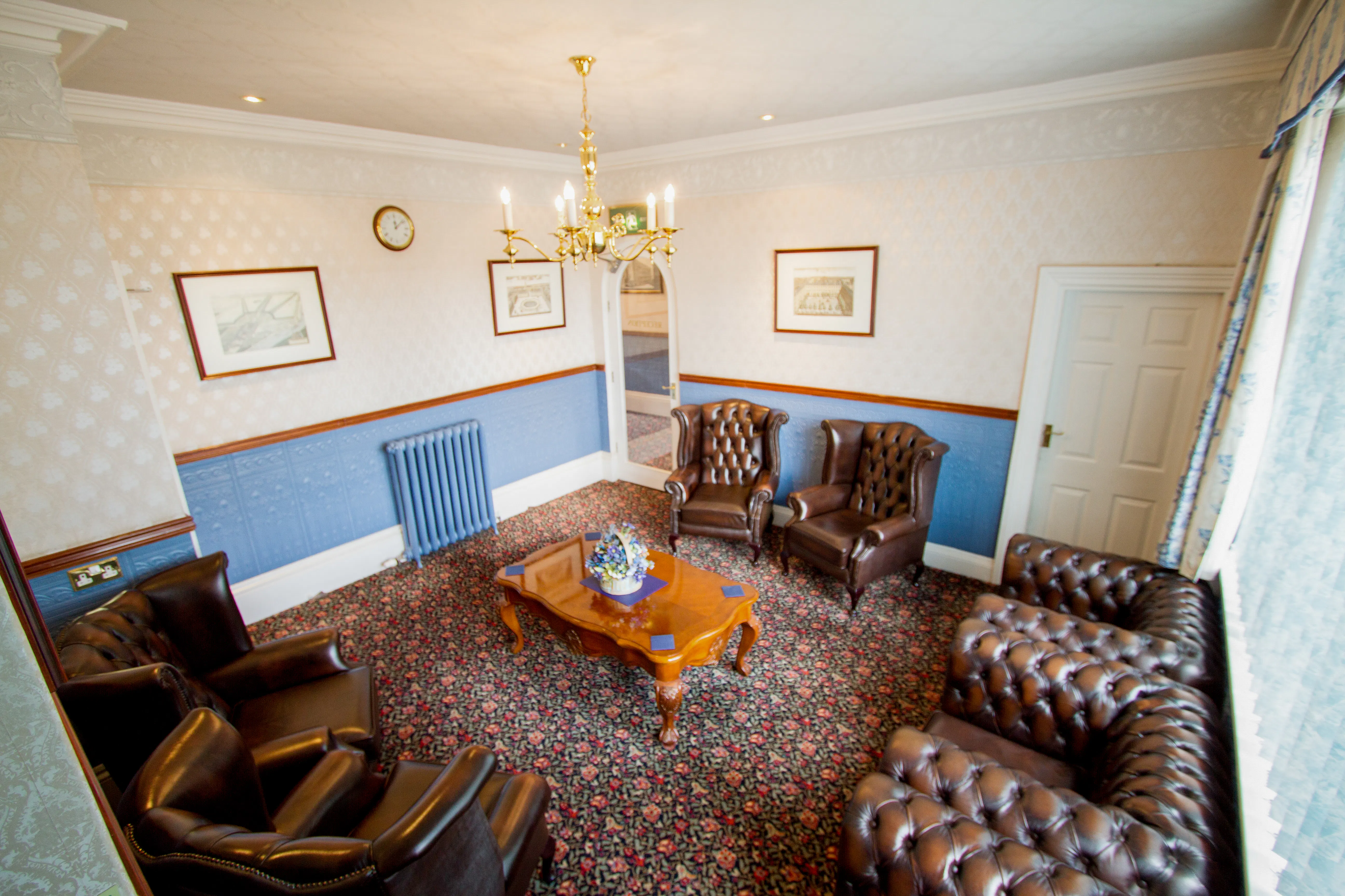 large room with traditional furnishings and Chesterfield dark brown leather sofa and armchairs