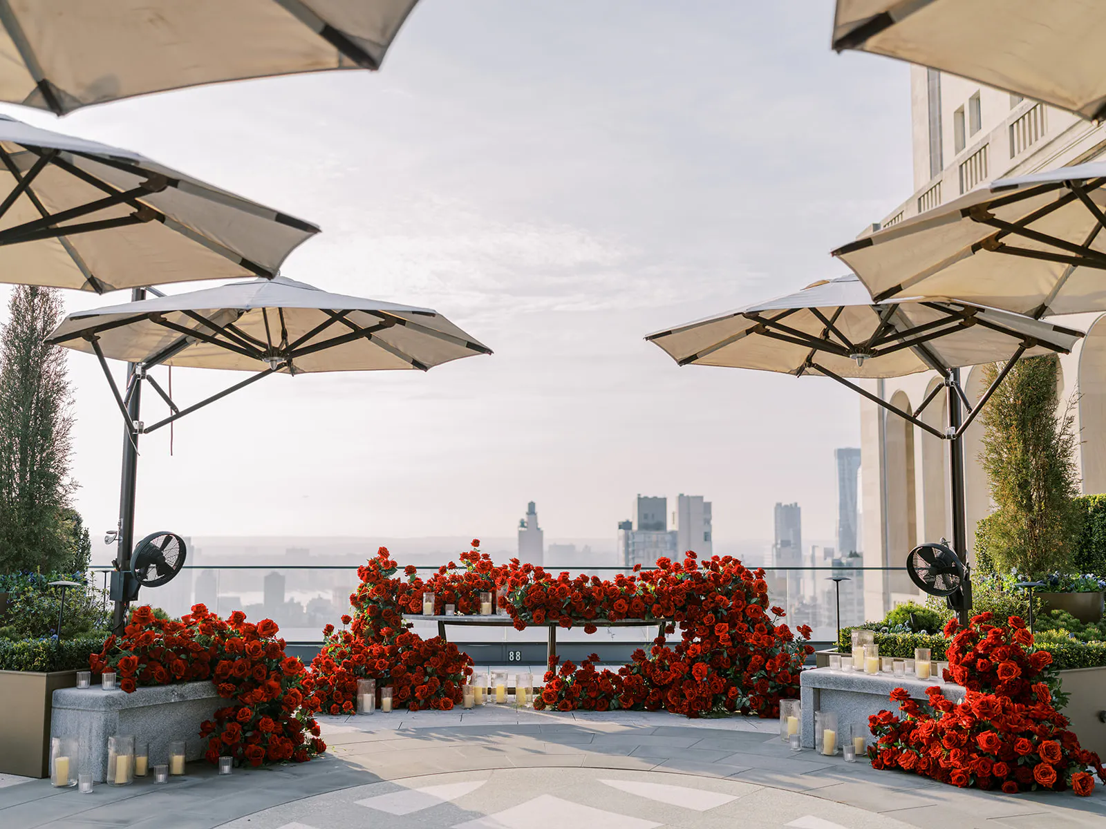 view of a new york from a rooftop with umbrellas and red roses