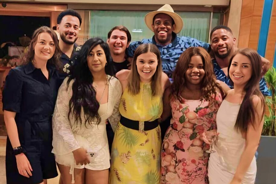 Nine people smiling and posing in a group at a team social event