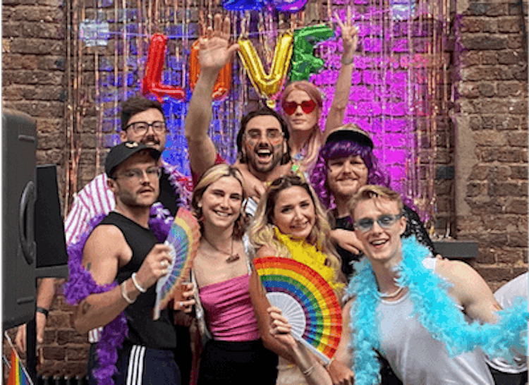 A group photo of eight Lendable employees posing in front of a rainbow 'Love is Love' sign at Lendable's annual Pride Party