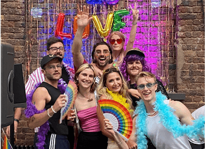 A group photo of eight Lendable employees posing in front of a rainbow 'Love is Love' sign at Lendable's annual Pride Party