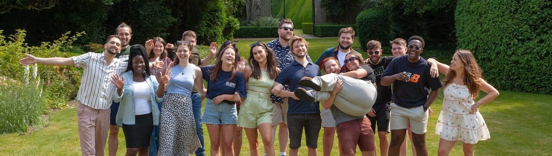 A group photo of the Lendable operations team smiling and waving at the camera in a country garden