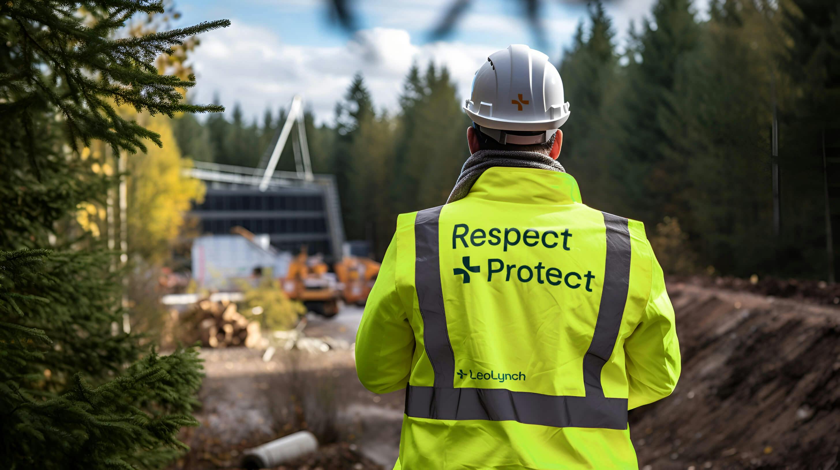 A male engineer on site. He is wearing Leo Lynch-branded 5 point PPE, including 'Respect + Protect' written on the back of his jacket