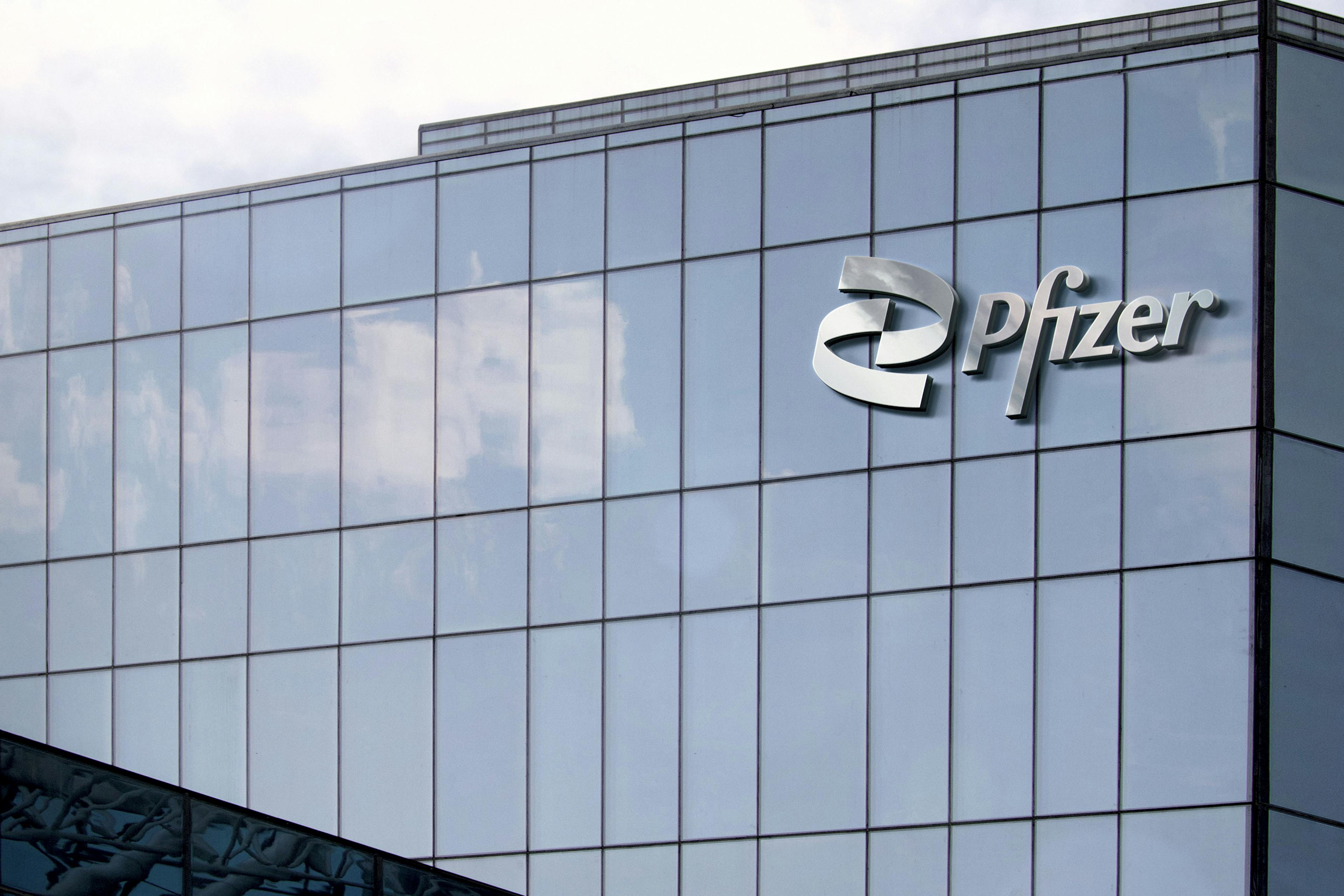 A cropped view of a glass skyscraper. Pfizer's name and logo is on the building.