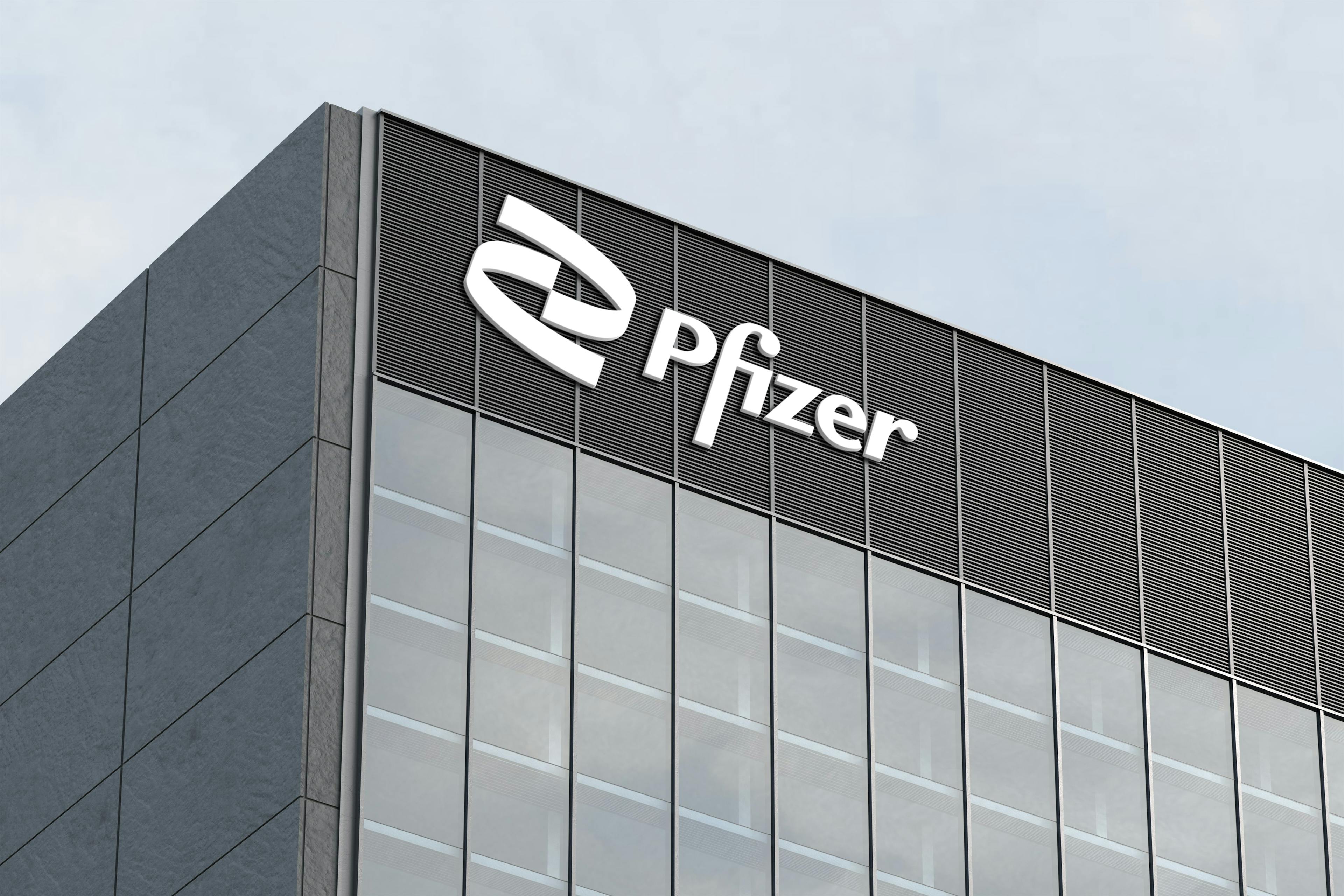 A cropped view of a concrete and glass skyscraper. Pfizer's name and logo is on the building.