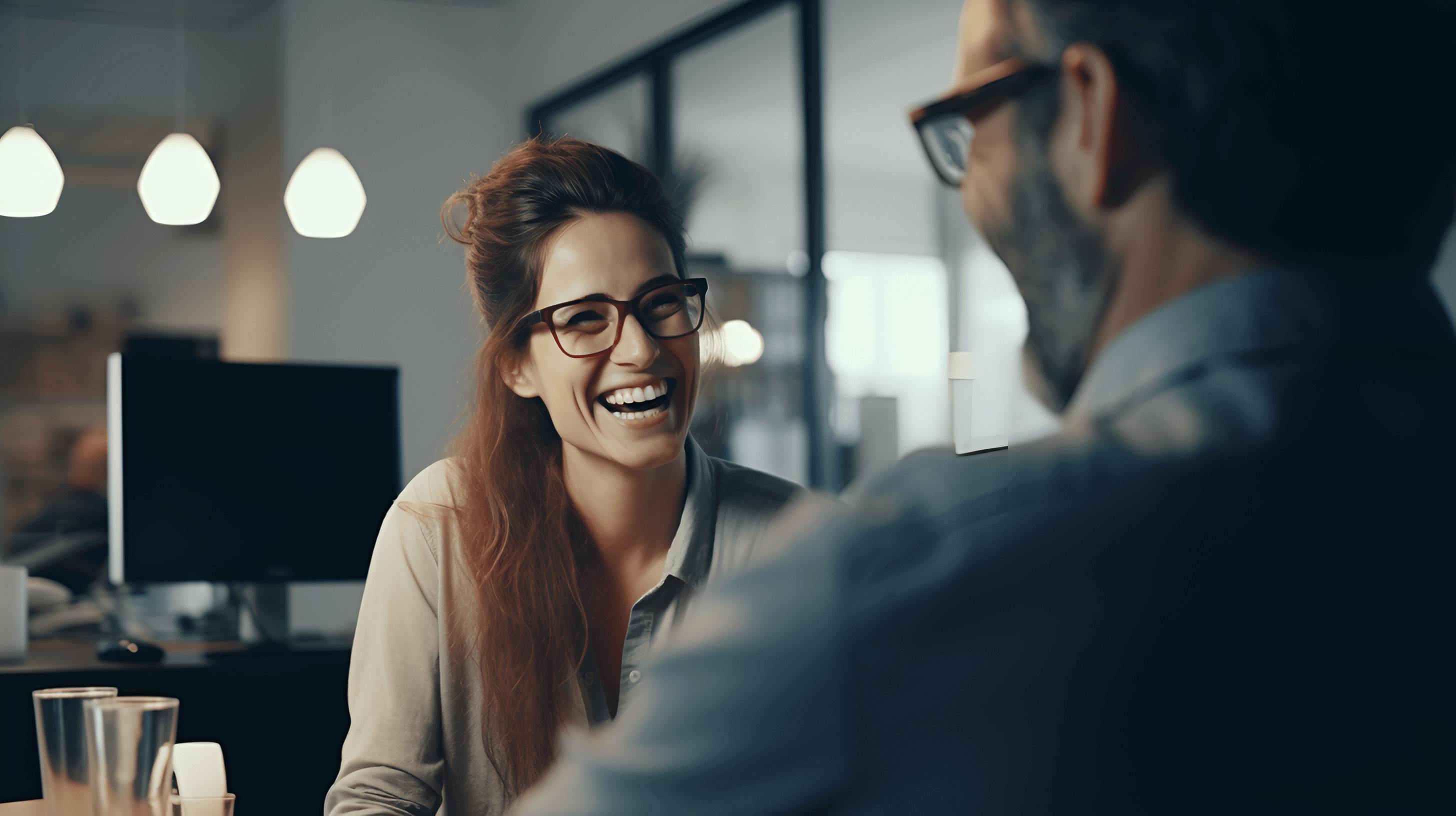 Two colleagues working together in an office. They are having a conversation and laughing.