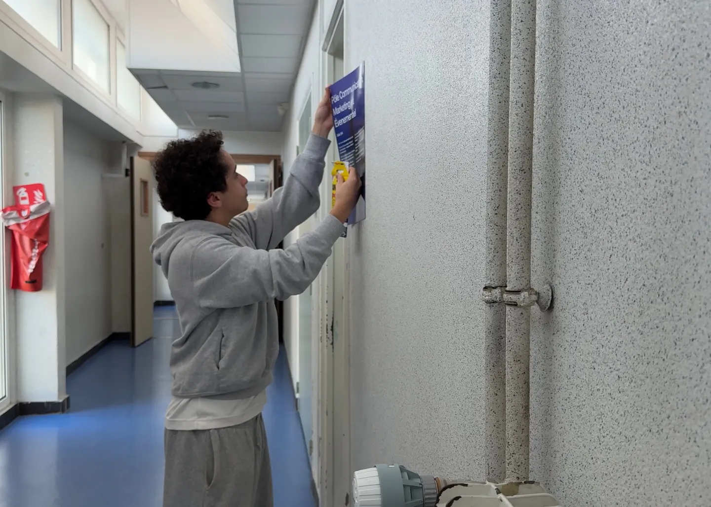 Un ancien affiche le programme d’un pôle métier dans un couloir du lycée, en décembre 2025