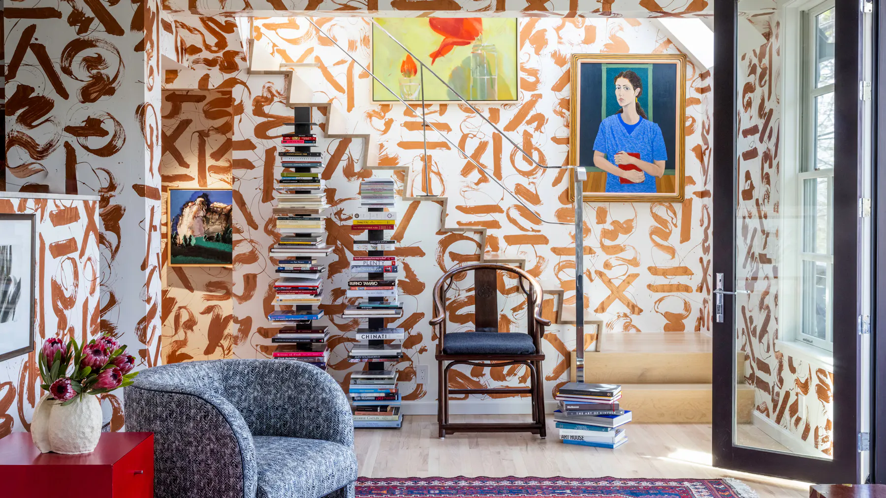 Interior design with hand-painted abstract mural walls, floating staircase, stacked books, and curated art-filled reading nook